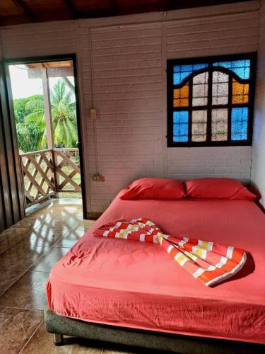 a bed in a bedroom with a window and a red bedspread at Cabaña Bamel in San Antero