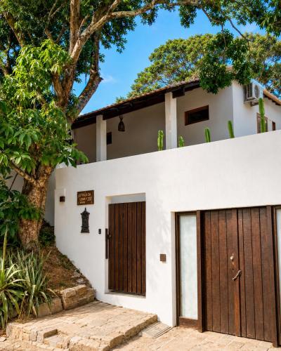a house with two garage doors and a tree at Pousada Narval Buzios in Búzios