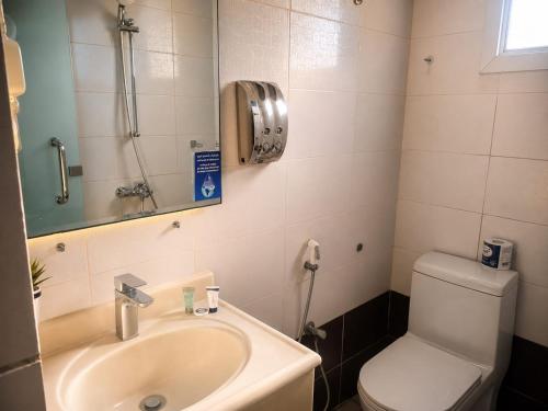 a bathroom with a sink and a toilet and a phone at Elaf Al Sharqyah Hotel -Alaziziah فندق ايلاف الشرقية العزيزية in Al Khobar