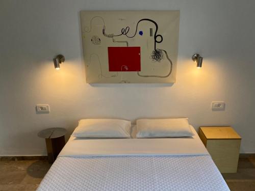a bedroom with a bed and a painting on the wall at Daphne Bungalows in Tolo