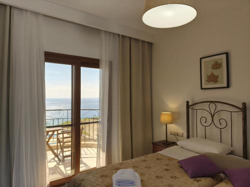 a bedroom with a bed and a view of a balcony at Aegean Blue Studios in Afitos