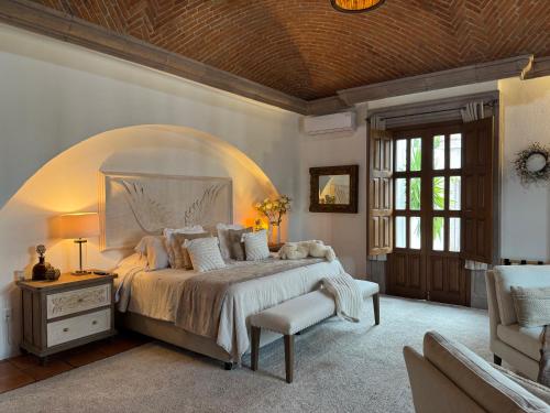 a bedroom with a large bed and a chair at Tres Fuentes Dickinson Hotel Boutique in San Miguel de Allende