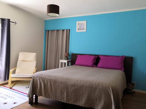 a bedroom with a bed with purple pillows and a chair at Ti Bleunv-nevez in Moëlan-sur-Mer