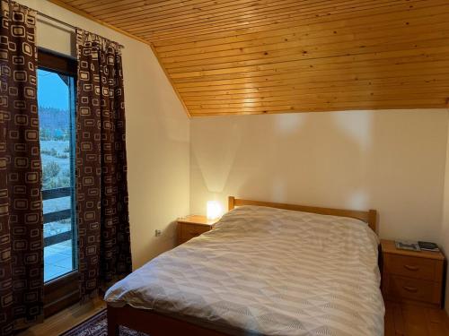 a bedroom with a bed and a large window at Wolf Chalet in Motički Gaj