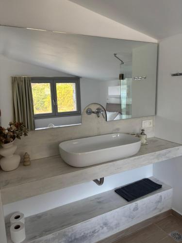 a white bathroom with a sink and a mirror at Almira Seaside Suites in Áyios Dhimítrios