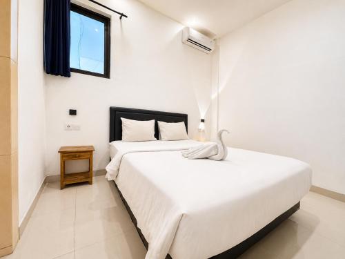 a white bedroom with two beds and a window at Suardana Inn's in Kuta
