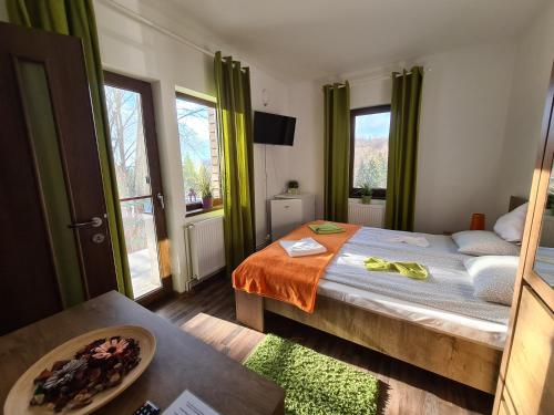 a bedroom with a bed with green curtains and a table at Vila Laura 1 in Sovata