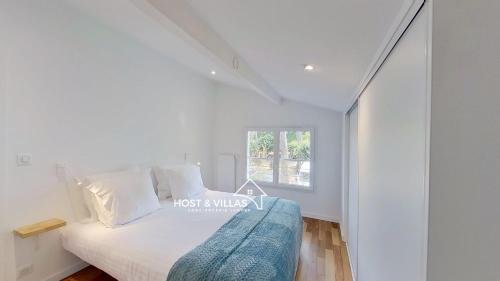 a white bedroom with a bed and a window at Host Villas LA TIRMANAISE Capbreton in Capbreton