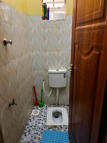 a small bathroom with a toilet with blue tiles at Petalluxe k24 in Narok