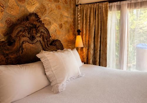 a bed with white pillows in a room with a window at Segredo da Serra Pousada Boutique in Tiradentes