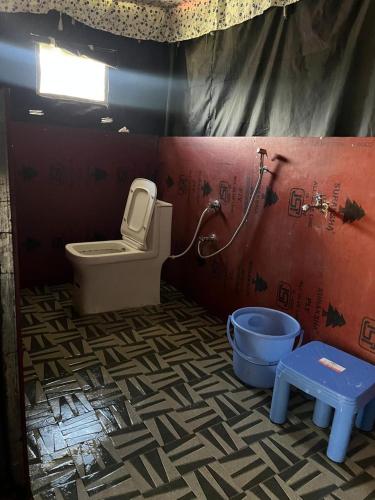 a bathroom with a toilet and a bucket in it at Chaukhamba Camp Stay in Chopta