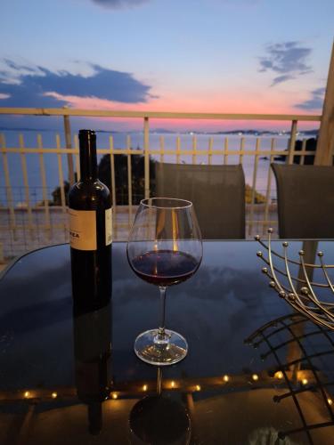 a bottle of wine and a wine glass on a table at Waterfront Penthouse in Saronida
