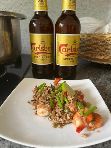 two bottles of beer sitting next to a plate of food at Skyline & bitcoin coffee lodge in Kalutara