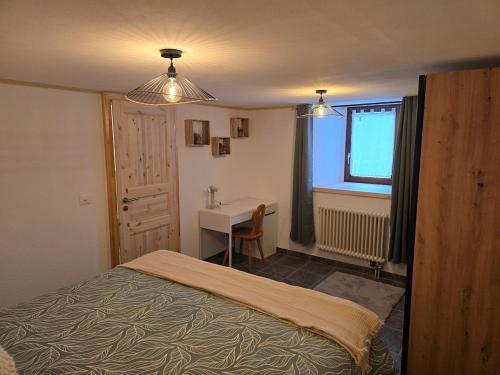 a bedroom with a bed and a desk and a window at Le Repos du Jorat in Saint-Maurice