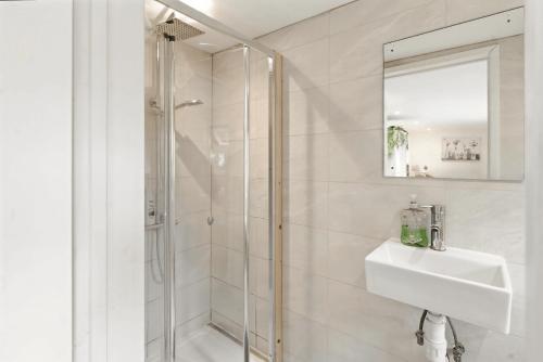 a white bathroom with a shower and a sink at Garden Studio En-Suite in Egham