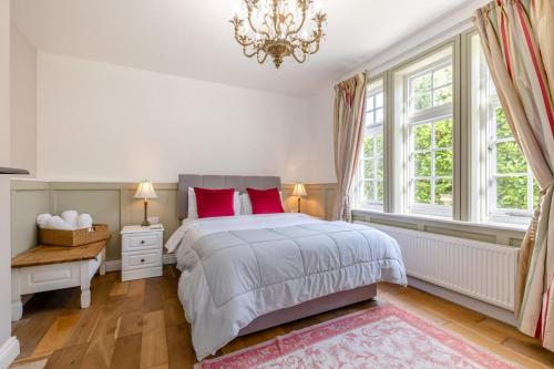 a bedroom with a bed with red pillows and a chandelier at 5 Bed in Belper oc-b29775 in Belper