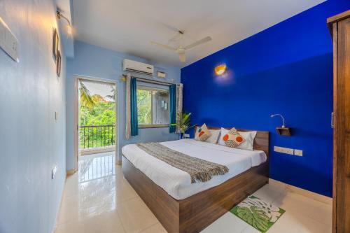 a blue bedroom with a bed with a blue wall at 2bhk Excella Apartment at Vagator in Vagator
