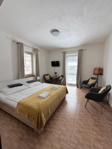 a bedroom with a large bed and chairs in it at Hřensko 27 Apartmány in Hřensko