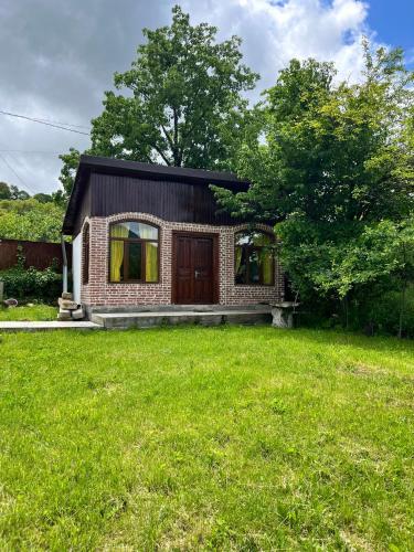 a small brick house with a grass yard at Marisi Cottage - კოტეჯი მარისი in Ambrolauri