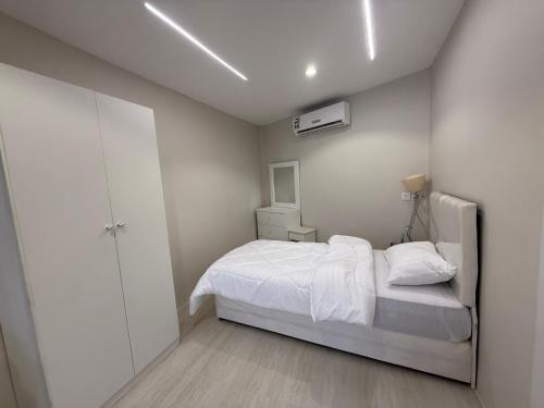 a small white bedroom with a bed and a closet at ستديو in Al Baha