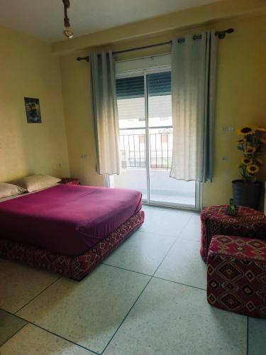 a bedroom with a purple bed and a sliding glass door at Dar LFarah Agadir & Rooftop in Agadir