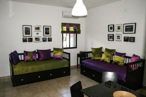 two beds in a room with purple and green pillows at Pedras Del Rei Holiday House in Tavira