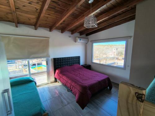 a bedroom with a purple bed and a window at Altos Aparts cabañas in Estancia Vieja