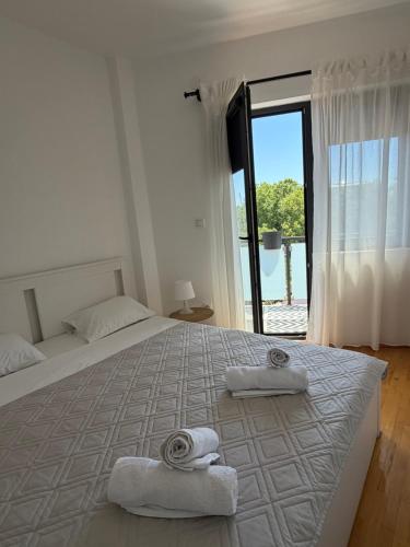 a white bedroom with a large bed with towels on it at Apartman Petrovic in Vranje