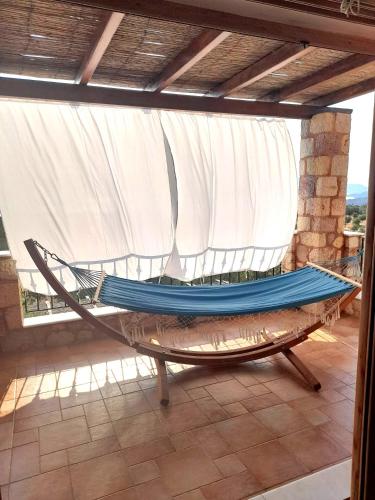 a hammock sitting on a patio with a window at "Villa Othon-Leni" - Panoramic Sea View & Traditional Luxury in Paralia Demonias
