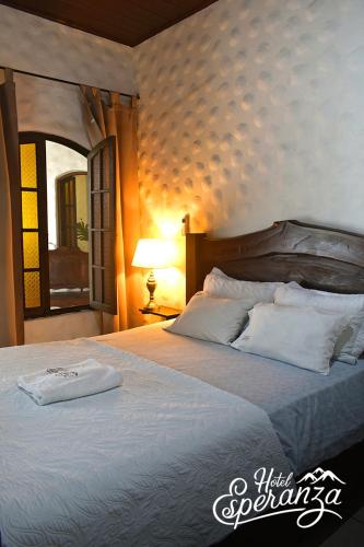 una camera da letto con un grande letto con cuscini bianchi di Hotel Esperanza Estelí a Estelí