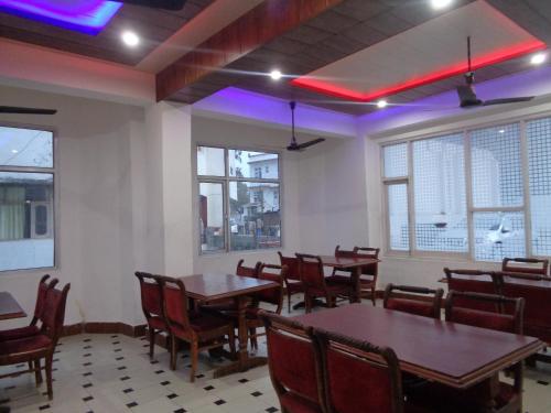 a dining room with tables and chairs and purple lights at Hotel Ishan in Katra