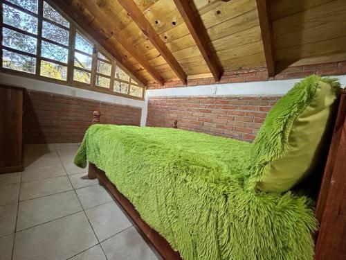 a large green bed in a room with a brick wall at Cabaña La Joyita By GEstores in Huasca de Ocampo