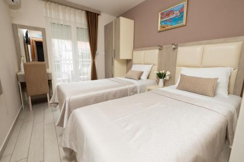 two beds in a hotel room with white sheets at Villa Bojana in Budva