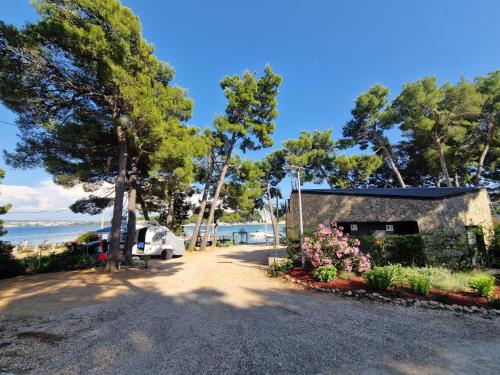 a car parked next to a building next to the beach at Taber Pašman – Mobile Homes in Pašman