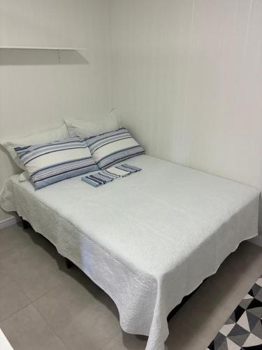 a bed with white sheets and pillows on it at Refúgio ensolarado a poucos passos do mar in Navegantes