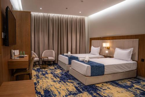a hotel room with two beds and a desk at H SAM Hotel in Taif