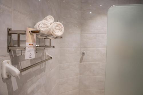 a bathroom with a shower with towels on a wall at H SAM Hotel in Taif