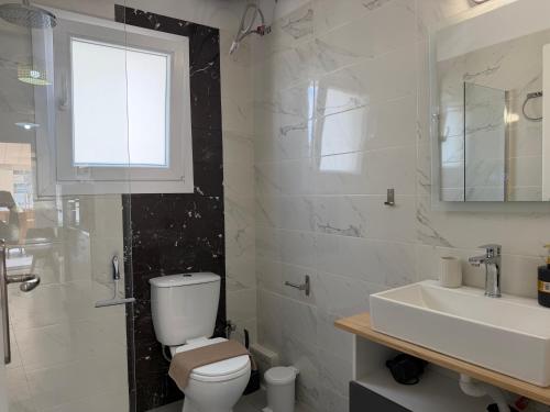 a bathroom with a toilet and a sink and a window at Piraeus Sea Loft in Piraeus