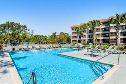 a swimming pool with chairs and a building in the background at HH Beach & Tennis 226C in Hilton Head Island