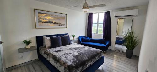 a bedroom with a bed and a blue chair at Oceanfront 3-bedroom Sub-Penthouse in Luquillo PR in Luquillo