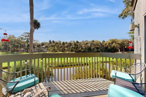 a balcony with chairs and a fence with trees at Breath'n Easy in Edisto Beach