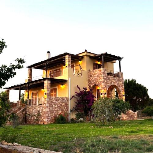 a large house with a stone wall at "Villa Othon-Leni" - Panoramic Sea View & Traditional Luxury in Paralia Demonias