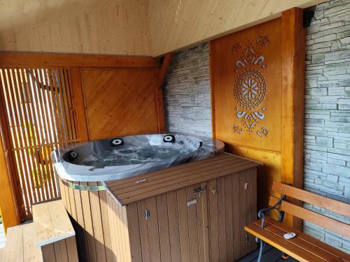 a bath tub in a wooden room with a bench at Pokoje Krystyna I Andrzej Łukaszczyk z WIDOKIEM NA GÓRY i Jacuzzi in Małe Ciche