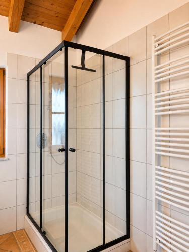 a glass shower in a bathroom with white tiles at NaturZeit Melleck in Schneizlreuth