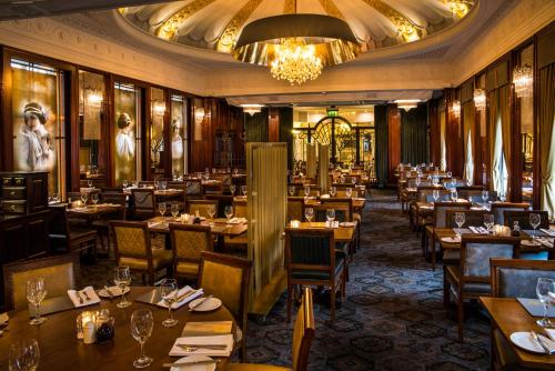 um restaurante com mesas e cadeiras de madeira e um lustre em The Royal Toby Hotel em Rochdale