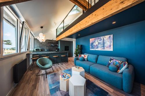 a living room with a blue couch and a kitchen at appartement Picasso - une évasion face à l'océan in Santec
