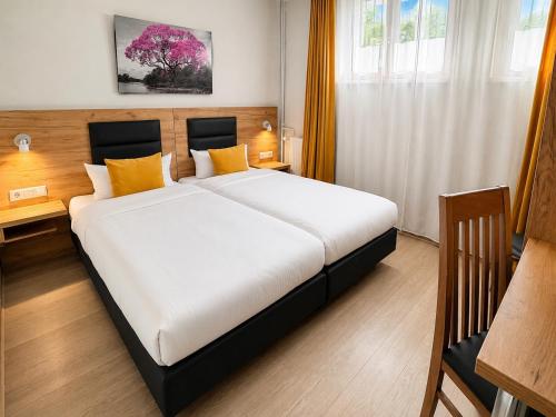 a bedroom with a large white bed with yellow pillows at Hotel Gute Hoffnung Pforzheim in Pforzheim