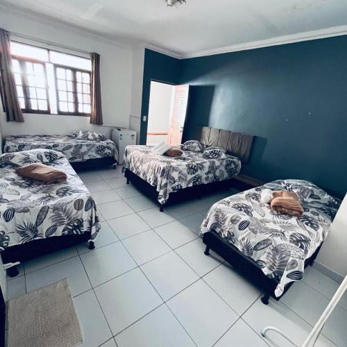 a room with three beds and a blue wall at Pousada Dipajuçara in Maceió