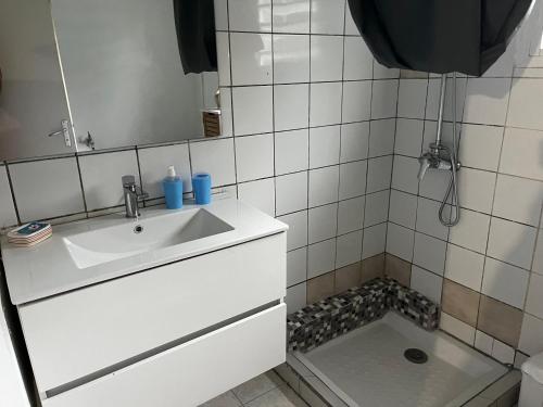 a white bathroom with a sink and a shower at Aux bambous in Rivière-Salée