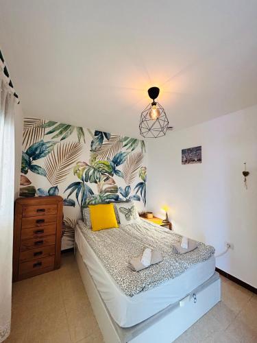 a bedroom with a bed with a tropical wallpaper at Ático Sol Vecindario in Vecindario